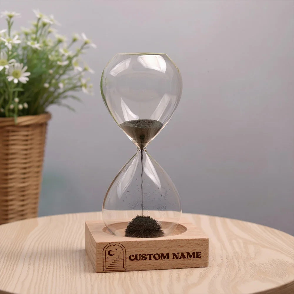 Reloj de arena personalizado con nombre y base de madera, diseño creativo con efecto natural en espejo, ideal para regalo de boda, fiesta y decoración elegante.